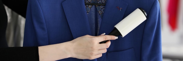 Skilled woman removes pellets from blue woolen coat with roller holding in hands female worker