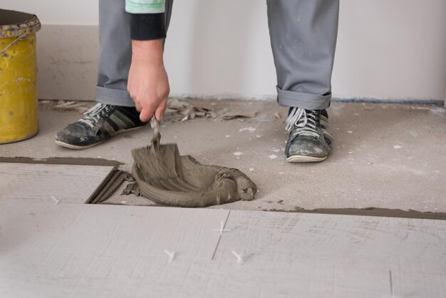 skilled worker installing the ceramic wood effect tiles on the floor Worker making laminate flooring on the construction site of the new apartment