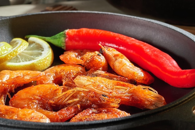 Skillet of fried shrimp with pepper and lemon Top view