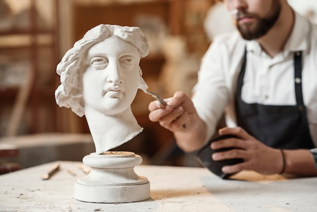 Skillful sculptor makes professional restauration of gypsum sculpture of womans head at the creative