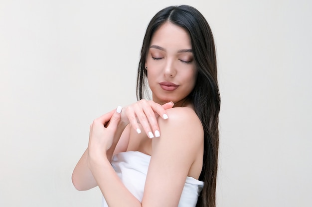 Skin and body care. Beautiful young woman in a towel touches her skin with her hands.