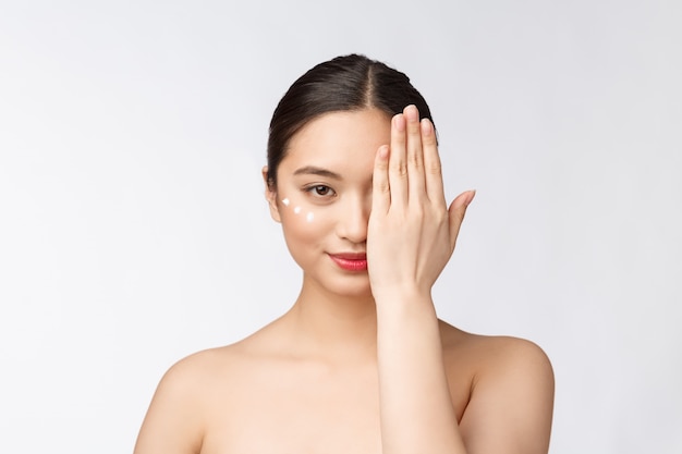 Skin care beauty woman Beauty woman smiling applying cream Beauty portrait of beautiful Asian Caucasian female model isolated on 
