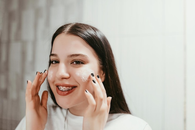 Cura della pelle primo piano di una giovane donna che si tocca il viso per applicare la crema idratante sfondo bianco foto di alta qualità