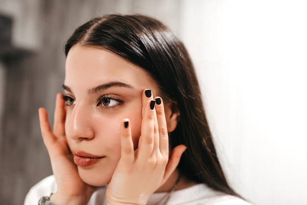 Skin care Close up of young woman touching her face to apply moisturizer White background Highquality photo