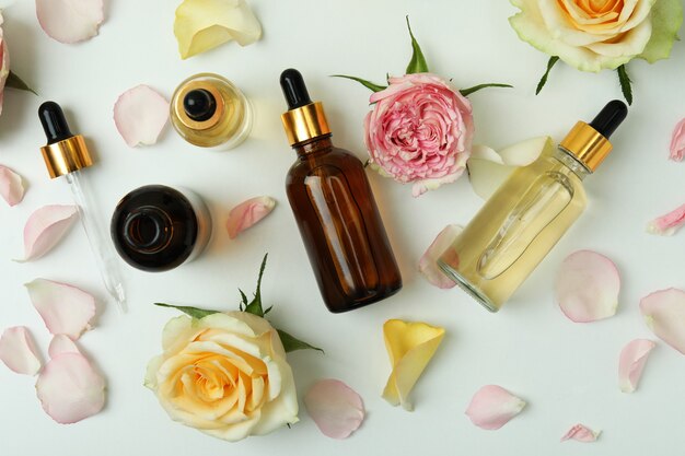 Skin care concept with essential rose oil on white, top view