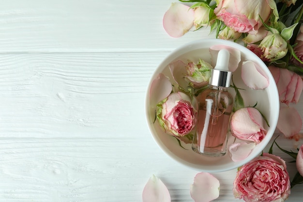 Skin care concept with essential rose oil on white wooden table