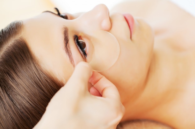 Skin care under the eyes, patches are applied to the young woman's eyes