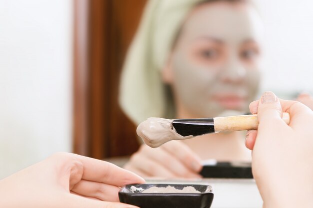 Skin care. Female hands making clay face mask.