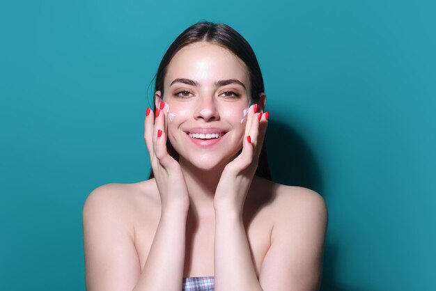 Skin care schoonheid portret van een mooie vrouw het aanbrengen van gezichtscrème geïsoleerd op studio achtergrond u