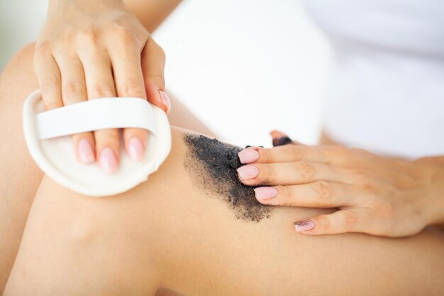 Skin care, woman applies black scrub with sea salt.