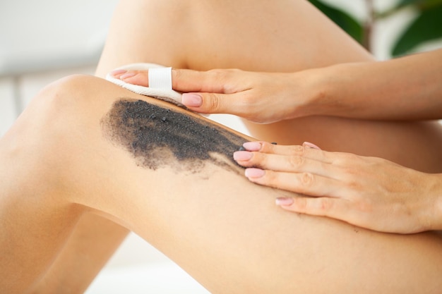 La donna per la cura della pelle applica uno scrub nero con sale marino