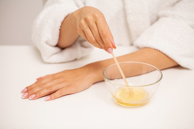 Skin care, a woman applies wax to her hand to remove hair