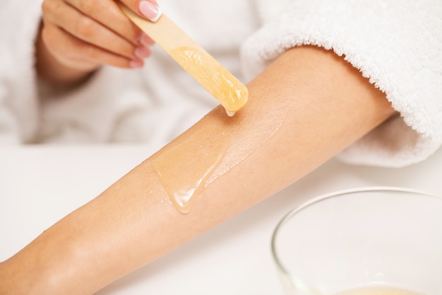 Skin care, a woman applies wax to her hand to remove hair