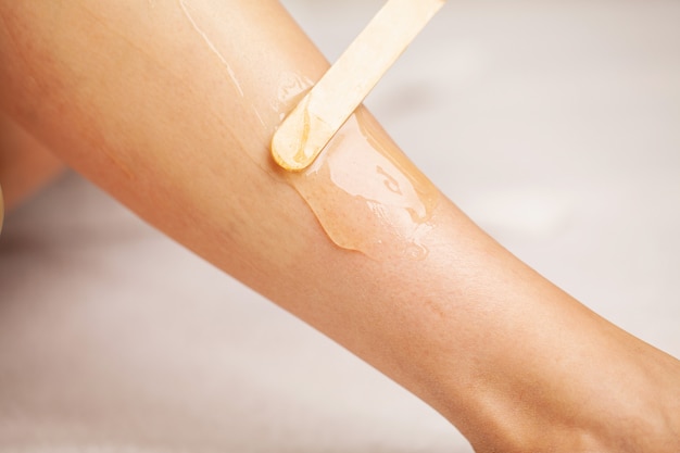 Skin care, a woman applies wax to her leg to remove hair