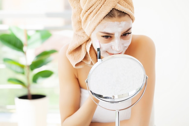 Skin care, young woman with beautiful facial skin applying mask on face