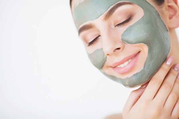 Photo skin care. young woman with cosmetic clay mask holding cucumber at her bathroom