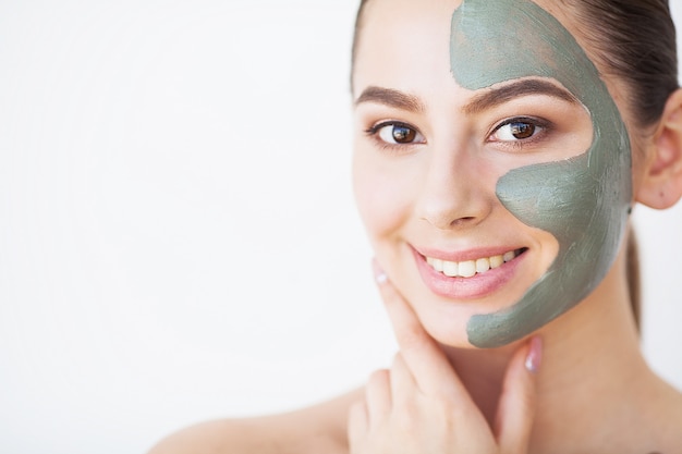 Skin Care. Young Woman With Cosmetic Clay Mask Holding Cucumber At Her Bathroom