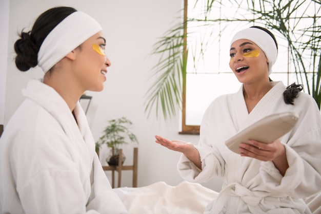 Skin cosmetics. Pleasant young women sitting together in the beauty salon while discussing skin cosmetics