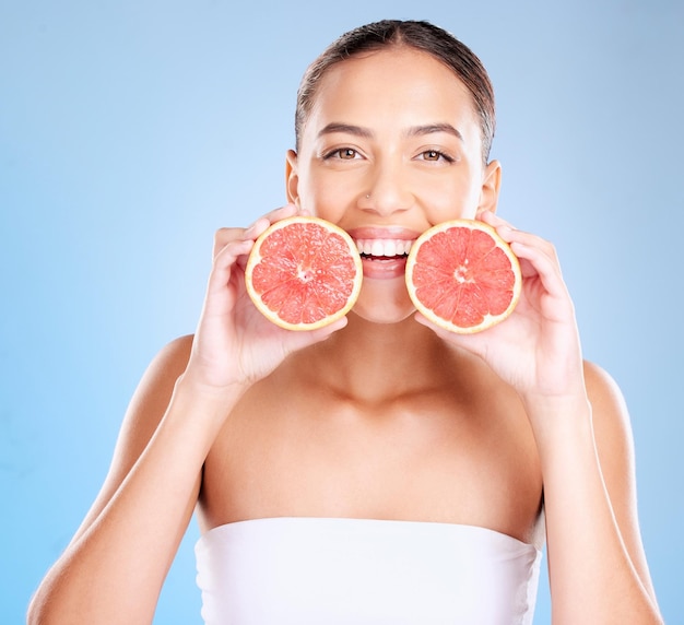 Skincare beauty and portrait of a woman with grapefruit for a natural organic and healthy face routine Cosmetic wellness and girl model from Mexico with a tropical citrus fruit by blue background