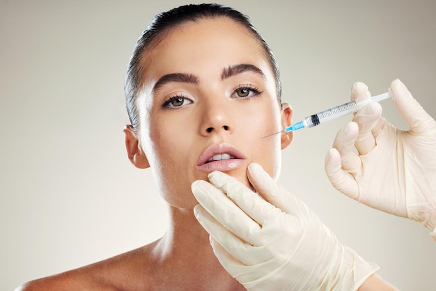 Skincare collagen and portrait of woman with injection in lips from healthcare professional anti aging treatment in studio Beauty model and aesthetic facial lip filler syringe on background