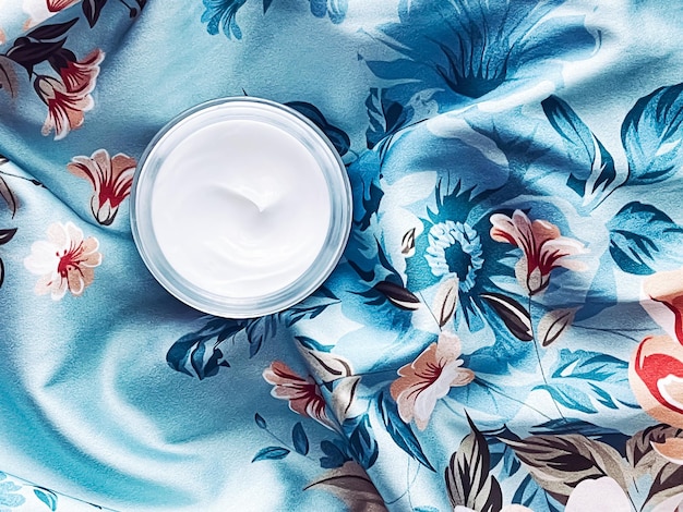 スキンケア化粧品は青い花の背景の美容製品フラットレイクローズアップのクリーム保湿ジャーに直面します