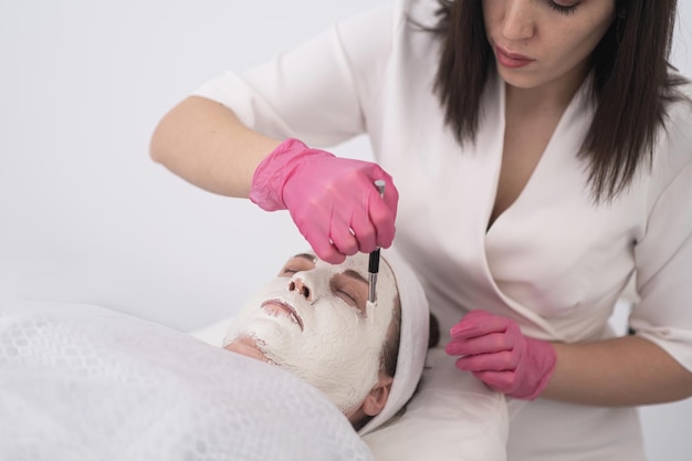 Skincare cosmetology and beauty treatments close up apply face masks to woman face cosmetologists