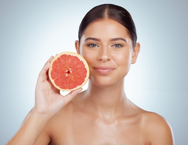 Skincare face and woman with grapefruit in studio isolated on a white background Portrait natural fruit and female model with vitamin c nutrition and healthy diet wellness or beauty cosmetics