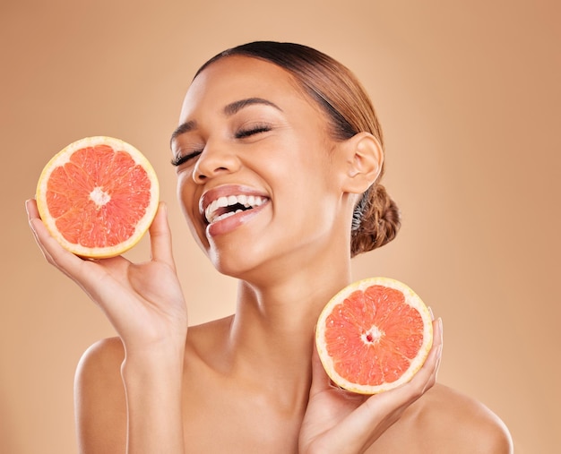 Photo skincare grapefruit and face of woman with laugh in studio for wellness facial treatment and natural cosmetics beauty spa aesthetic and happy girl with fruit for detox vitamin c and dermatology