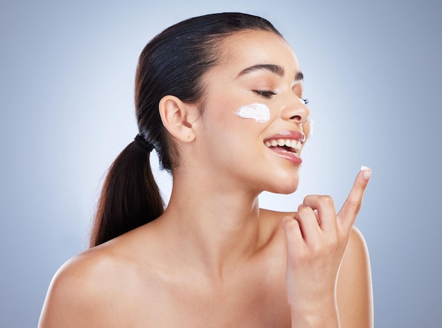 Skincare hand and happy woman with face cream in studio or anti aging collagen or hydration on grey background Finger smile and lady model with facial sunscreen lotion or beauty mask application
