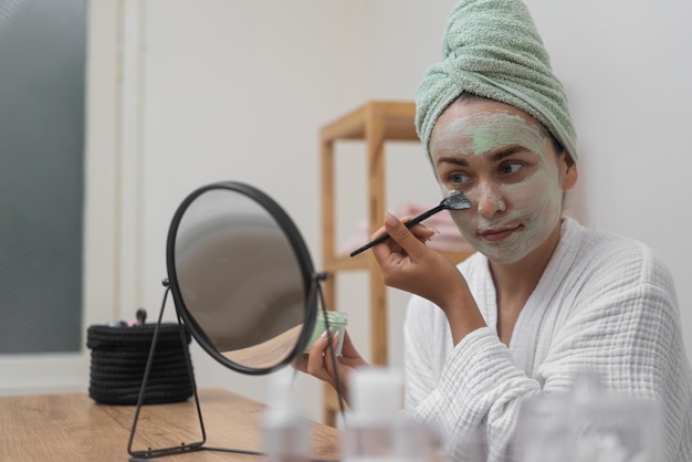 Skincare retreat beauty apply clay mask admiring her reflection during