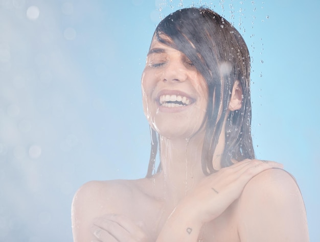 Душ по уходу за кожей и женщина, убирающая счастливые и расслабляющие велнес и брызги воды на синем фоне Модель волос и девушка в ванной комнате для ухода за волосами и увлажнения влаги