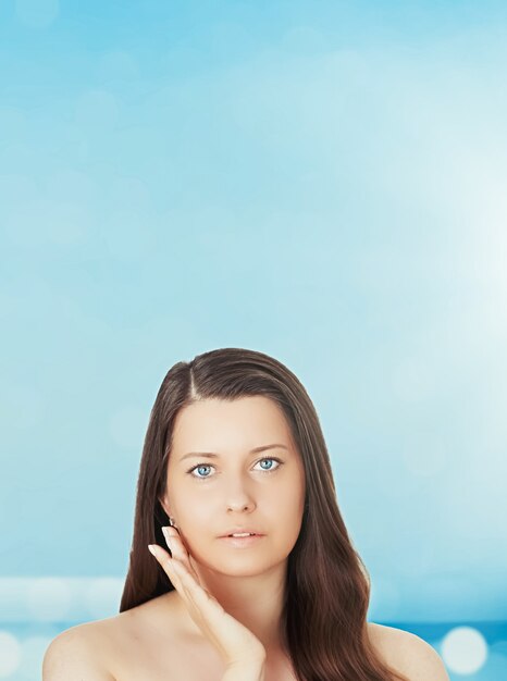 Skincare and sun protection in summer portrait of a beautiful young suntanned woman blue sea and sky on background beauty wellness and travel concept