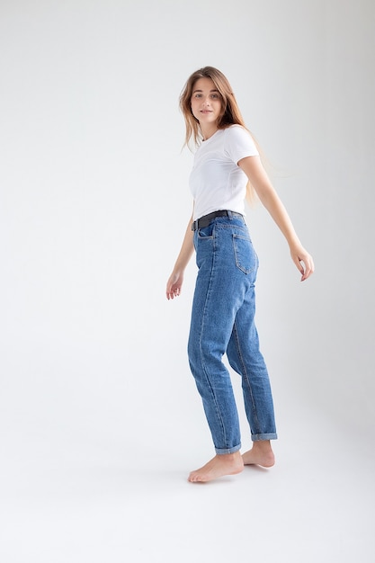 Skinny caucasian pretty girl standing on white studio background with bare feet