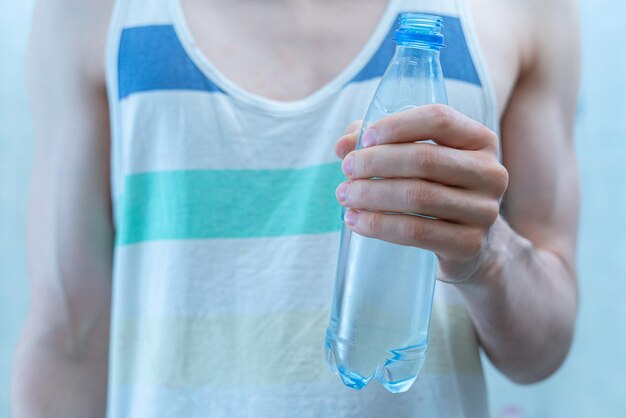 A skinny sportsman with a plastic bottle with pure water while workout