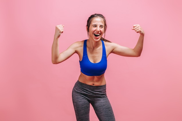 Skinny woman showing biceps on a pink wall