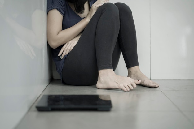 Skinny woman sitting with a weight scales