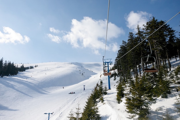 Skipiste en stoeltjeslift met besneeuwde bomen op zonnige dag. Skigebied Combloux, Franse Alpen