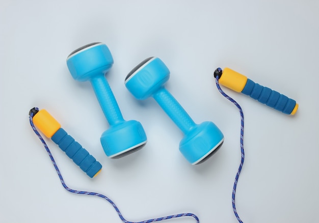 Skipping rope and dumbbells on white