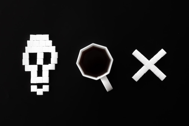 skull bones from sugar and cup of coffee on black background flat lay
