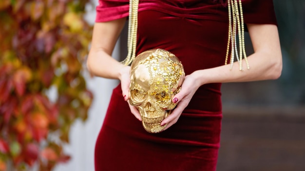 Skull decorated for day of the dead in Mexico with golden glitter in woman hands