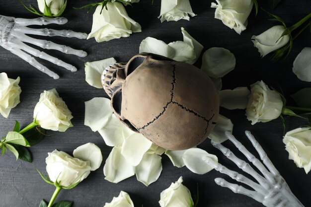 Skull hand bones and flowers on gray wooden background top view