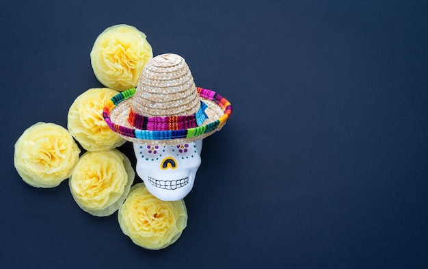 Skull with mexican hat and yellow paper cempasuchil flowers on black 