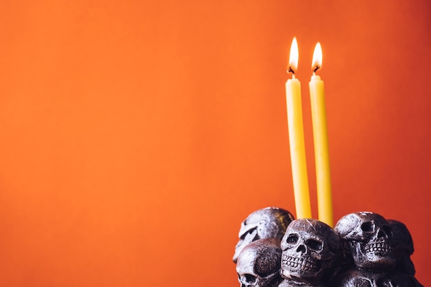 Skulls with candle burning on an orange color background. Free space for text