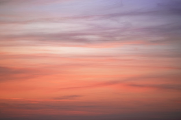 夕焼けの空と羽の雲。空の色が紫から濃いオレンジに変わります。