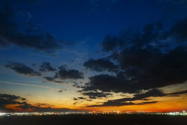 街灯のある街に沈む夕日の後、雲のある空。