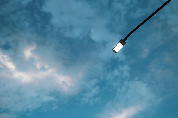 A sky with clouds and a lit street lamp