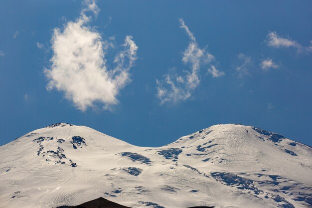 북 코카서스 산 Elbrus의 눈 덮인 피크 위에 구름과 하늘