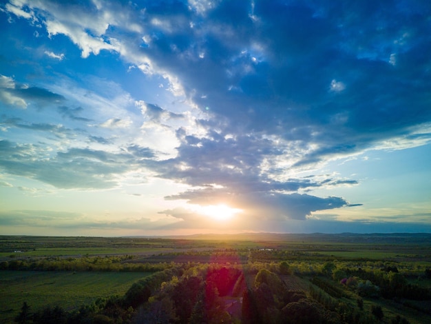 Sky with clouds and sun over fields and pastures