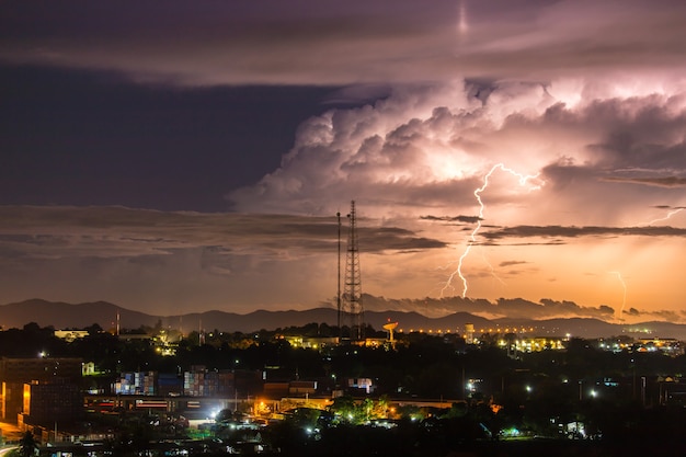 Sky with lightning striking hills behind small town