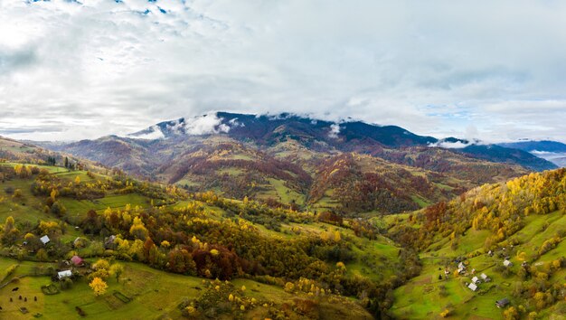 Sky with white and fluffy layer of clouds over green autumn hills